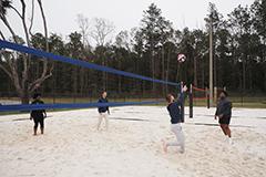 学生 playing sand volleyball on campus.